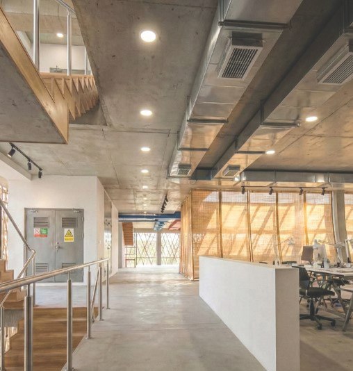 Interior render: circulation spine beside the studios, with the timber stair overhead, exposed ducting and bamboo mesh screens