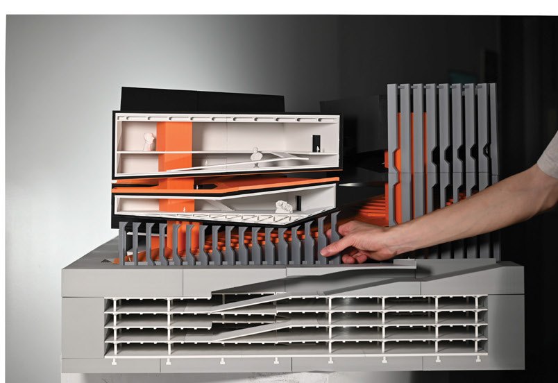 Sectional model — hand pulling a gallery volume out of the massing